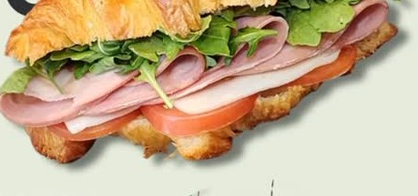 A freshly baked Elysian Cafe croissant sandwich with ham, tomato and arugula